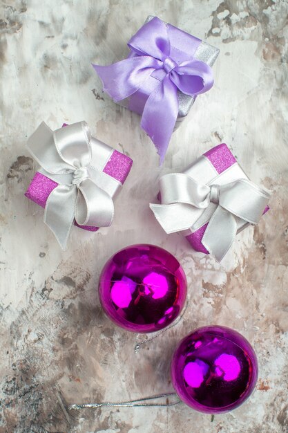 Vue verticale de trois cadeaux de Noël pour les membres de la famille et d'un accessoire de décoration sur le côté gauche sur fond de glace