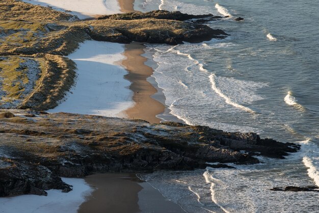 Vue à vol d'oiseau des vagues se brisant sur la plage avec des rochers sur le rivage