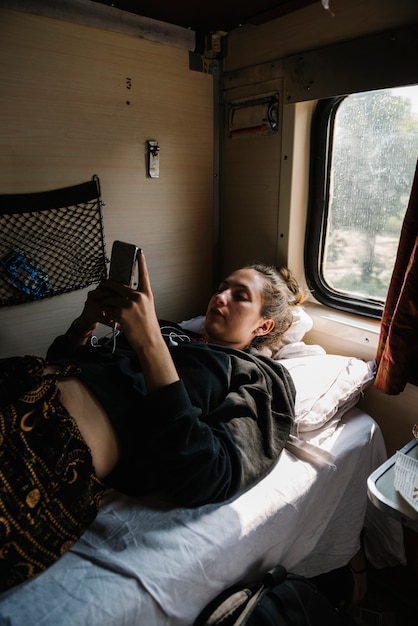 Western Backpacker utilisant son téléphone dans le train indien