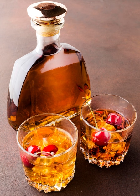Photo gratuite whisky grand angle sur les rochers avec des cerises et une bouteille