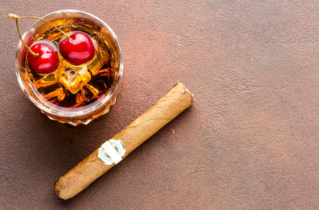 Whisky grand angle sur les rochers avec cerises et cigare avec copie-espace