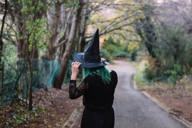 Witch on forest road holding hat