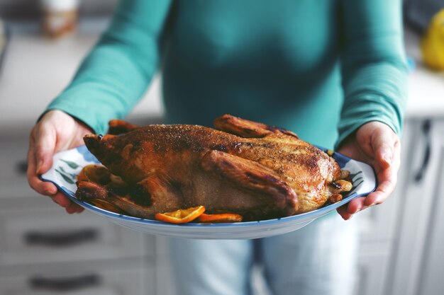 Woman cooking canard avec des légumes et le mettre du four. Mode de vie. Concept de Noël ou de Thanksgiving.