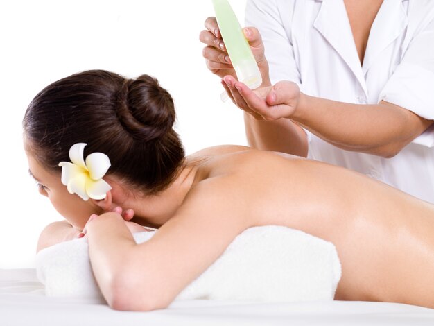 Woman heaving massage relaxant dans un salon de beauté avec des huiles aromatiques