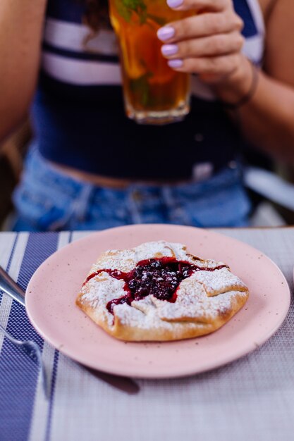 Woman in cafe avec thé glacé et tarte aux canneberges