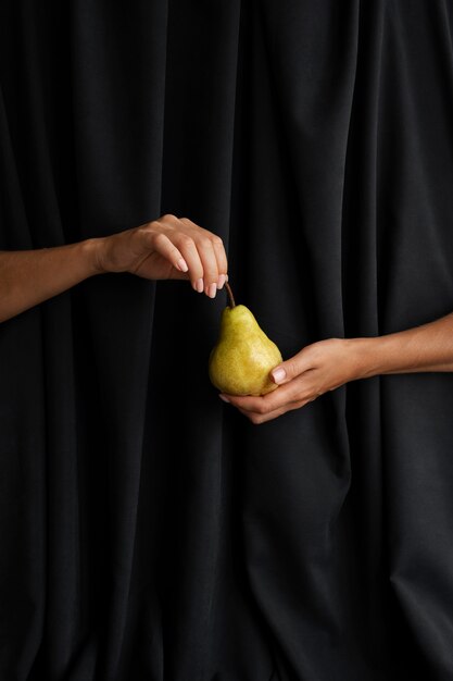 Woman's hands holding poire avec un fond sombre