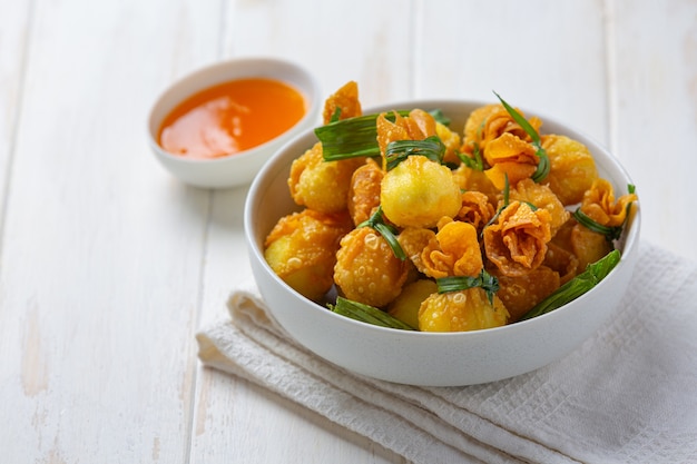 Wonton frit sur la surface en bois blanche.