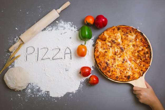 Word Pizza écrit sur de la farine avec une pizza savoureuse