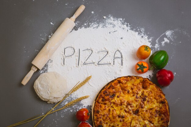 Word Pizza écrit sur de la farine avec une pizza savoureuse
