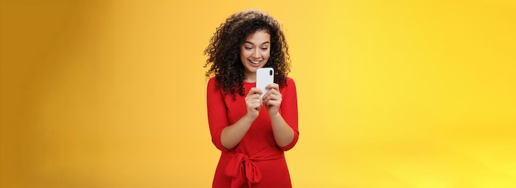 Photo gratuit wow nouveau téléphone mobile incroyable impressionné et étonné belle femme aux cheveux bouclés en robe rouge ho