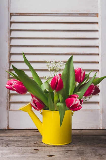 Yellow arrosoir avec de belles tulipes