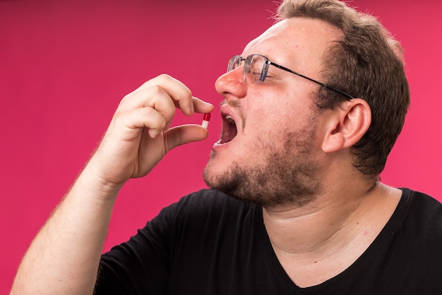 Photo gratuite avec les yeux fermés, un homme malade d'âge moyen essaie la pilule