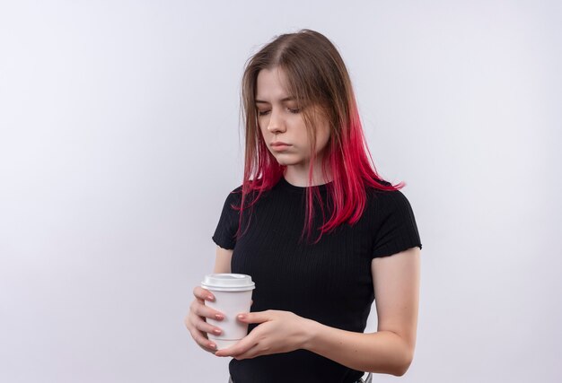 Avec les yeux fermés jeune belle fille portant un t-shirt noir tenant une tasse de café sur un mur blanc isolé