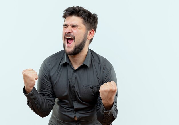 Avec les yeux fermés joyeux jeune homme d'affaires montrant oui geste isolé sur blanc