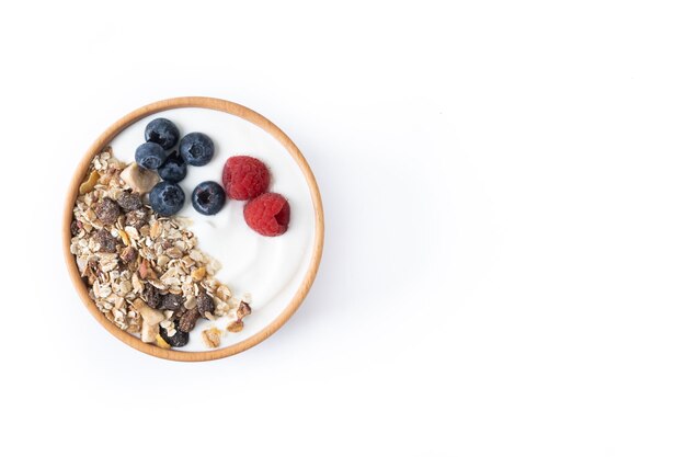 Yogourt aux baies et muesli pour le petit déjeuner dans un bol isolé sur fond blanc