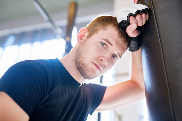 Young Boxer s'appuyant sur un sac de boxe