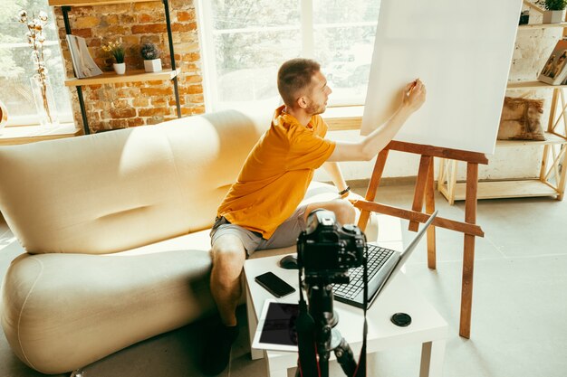 Young caucasian male blogger with professional camera record video review of gadgets at home