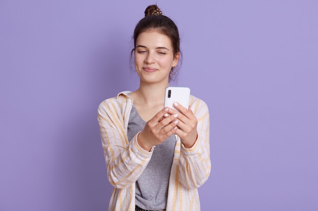 Young happy smiling young woman wearing casual wear, posant contre le mur lilas