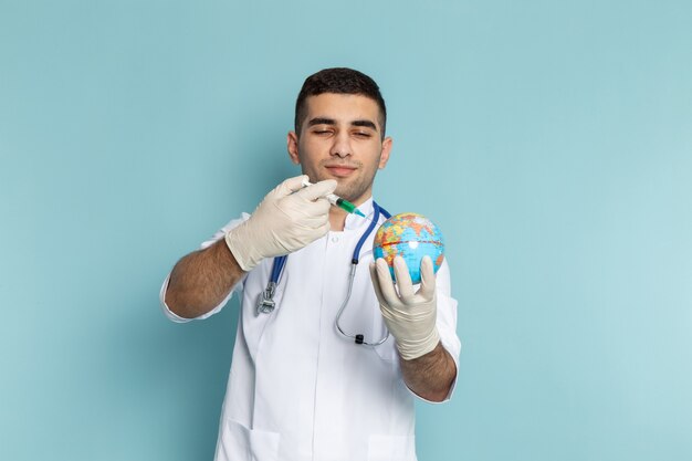 Young male doctor in white suit with blue stethoscope holding injection