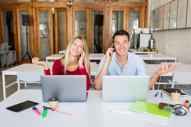 Young smiling happy man and woman working on laptop in open space co-working office room