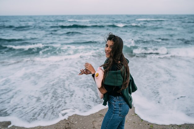 Young woma tire sur un smartphone les vagues de la mer