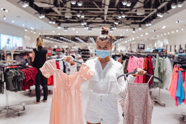 Young woman shopping vêtements en boutique de vêtements avec masque de protection