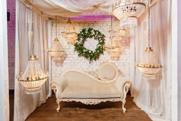 Zone photo élégante décorée de lampes de canapé et d'une couronne de verdure sur fond de mur de briques blanches