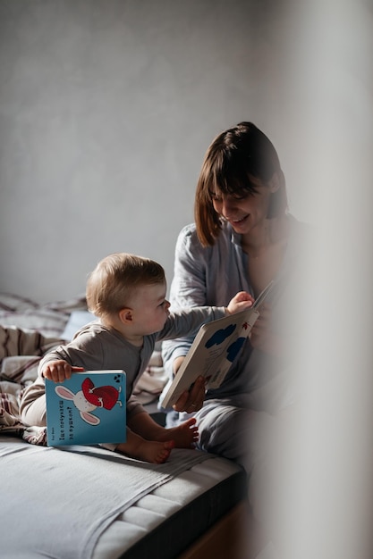 02032022 Vinnitsa Ukraine jeune mère et petite fille se sont réveillés au lit en s'amusant en regardant un livre