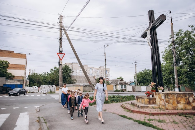 070722 Irpin Ukraine les enfants et leurs enseignants marchent par paires tenant un stylo et se cachent dans un barrage routier fait de sacs de sable lors d'un avertissement de raid aérien