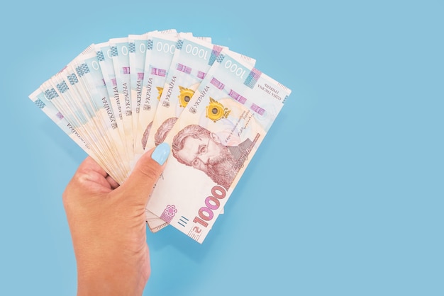 1000 hryvnia dans la main d'une femme sur bleu