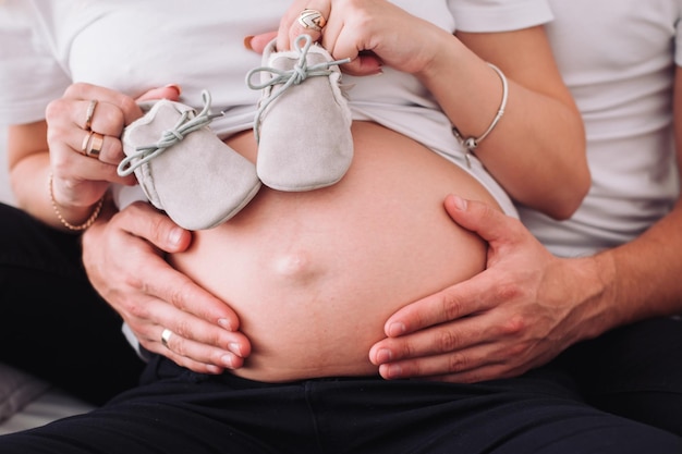 100822 Vinnytsia Ukraine La future mère et le père tiennent les chaussures du bébé près du ventre