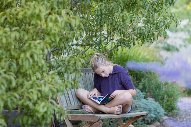 11 ans, fille, assis sur un banc en lisant un livre