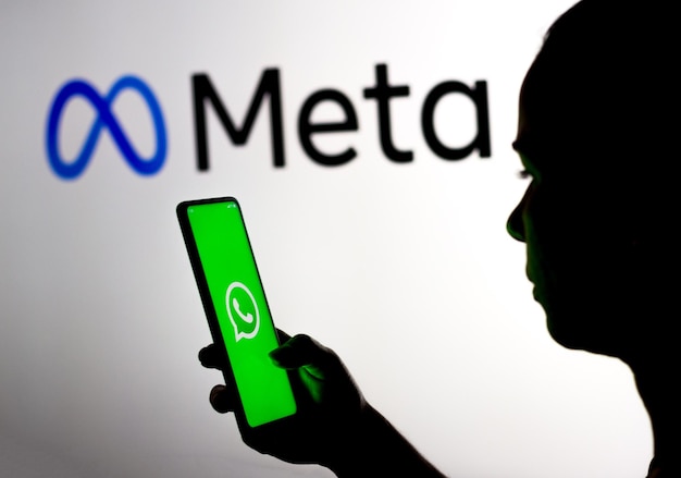 16 mars 2022 Brésil Sur cette photo, une femme tient un smartphone avec le logo WhatsApp affiché à l'écran avec le logo Meta Platforms affiché en arrière-plan