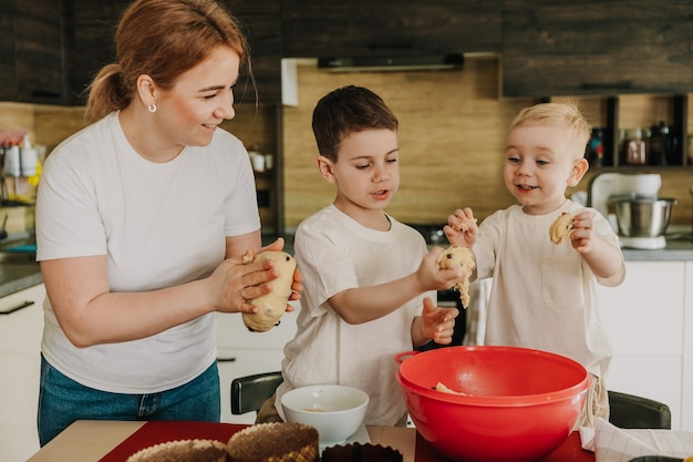 18112018 Vinnitsa Ukraine maman avec des enfants pétrit la pâte pour de délicieuses pâtisseries qu'ils préparent dans la cuisine à la maison