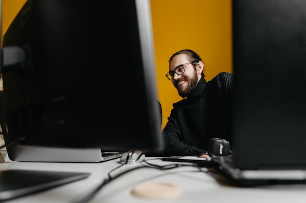 19032021 Vinnitsa Ukraine portrait d'un homme élégant avec des lunettes travaillant au bureau sur des ordinateurs photo prise derrière les moniteurs sur lesquels il travaille