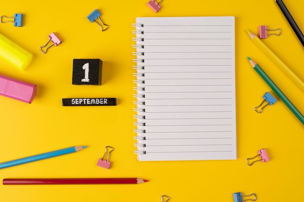 1er septembre sur un calendrier en bois parmi les fournitures d'étude sur fond jaune Retour à l'école