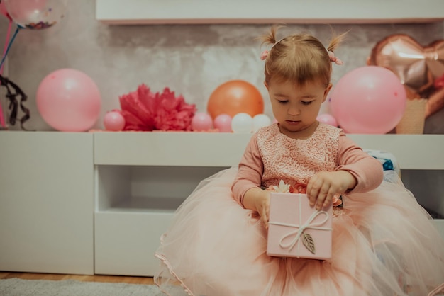 2 ans bébé fille en robe rose avec son premier gâteau d'anniversaire joyeux anniversaire carda jolie petite fille célèbre son premier anniversaire entouré de cadeaux