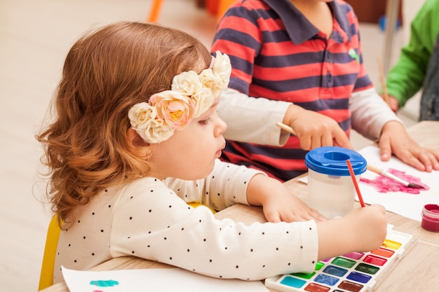 2 ans Les enfants apprennent à peindre avec un pinceau et des aquarelles sur papier à la maternelle