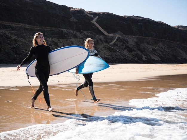 2 surfeuses sur la plage courant vers l'eau