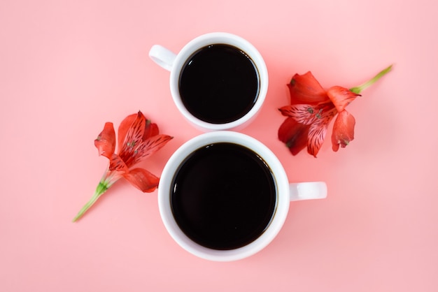 2 tasses de café avec des fleurs sur fond rose.