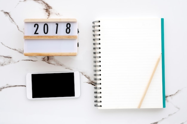 2018 boîte en bois, papier vierge pour ordinateur portable, téléphone intelligent avec écran blanc sur fond de marbre blanc