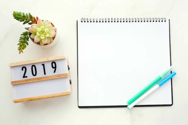 2019 sur une boîte en bois, papier vierge sur fond de table en marbre blanc