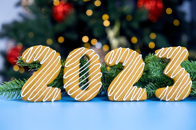 2023 Numéro de cookie en pain d'épice avec glaçage blanc avec sapin de Noël et lumières de Noël sur fond bleu Joyeux Noël et bonne année