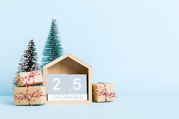 25 décembre composition de Noël sur fond coloré avec un calendrier en bois avec une boîte-cadeau jouets babiole copie espace