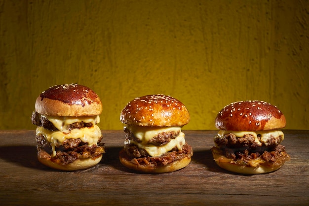 3 cheseburgers de tailles différentes sur une table en bois.