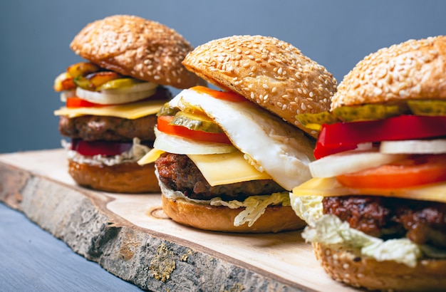 3 hamburgers différents sur une étagère en bois.