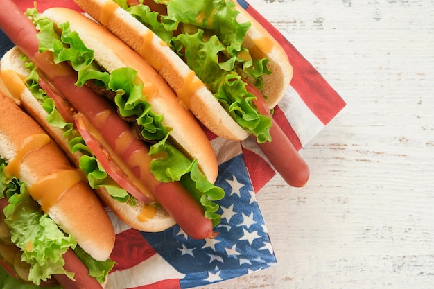 4 juillet Jour de l'Indépendance américaine Nourriture de pique-nique traditionnelle Hot-dog avec chips et cocktail Drapeaux américains et symboles des États-Unis Vacances de pique-nique patriotique sur fond en bois blanc Vue de dessus