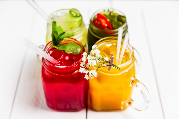 4 limonades d'été rafraîchissantes différentes en pots, rouge, orange, jaune et vert