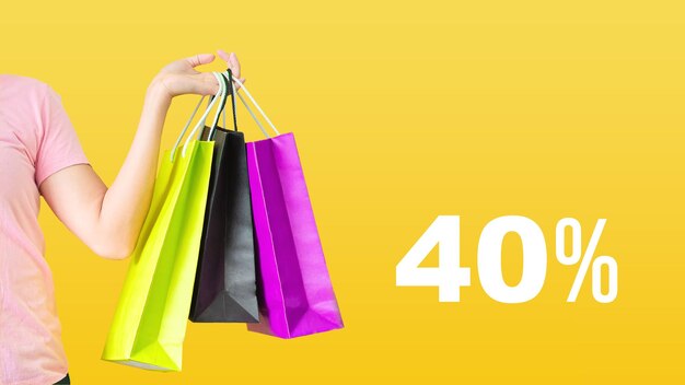 40 % de remise.Vente avec des mains féminines tenant des sacs à provisions sur fond jaune. Black Friday et concept de vente.