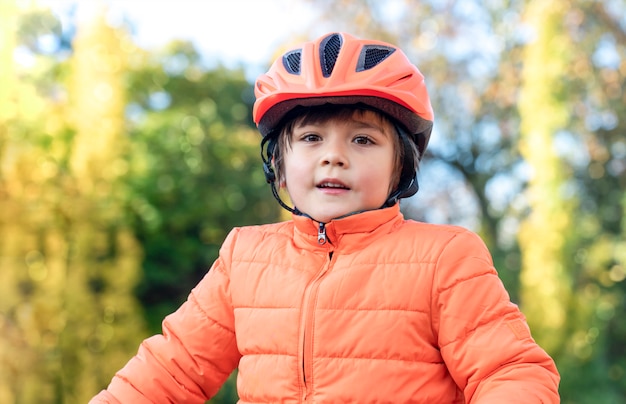 6-7 ans race mixte Asian-Caucasian boy porte un casque de vélo debout à l'extérieur dans le parc